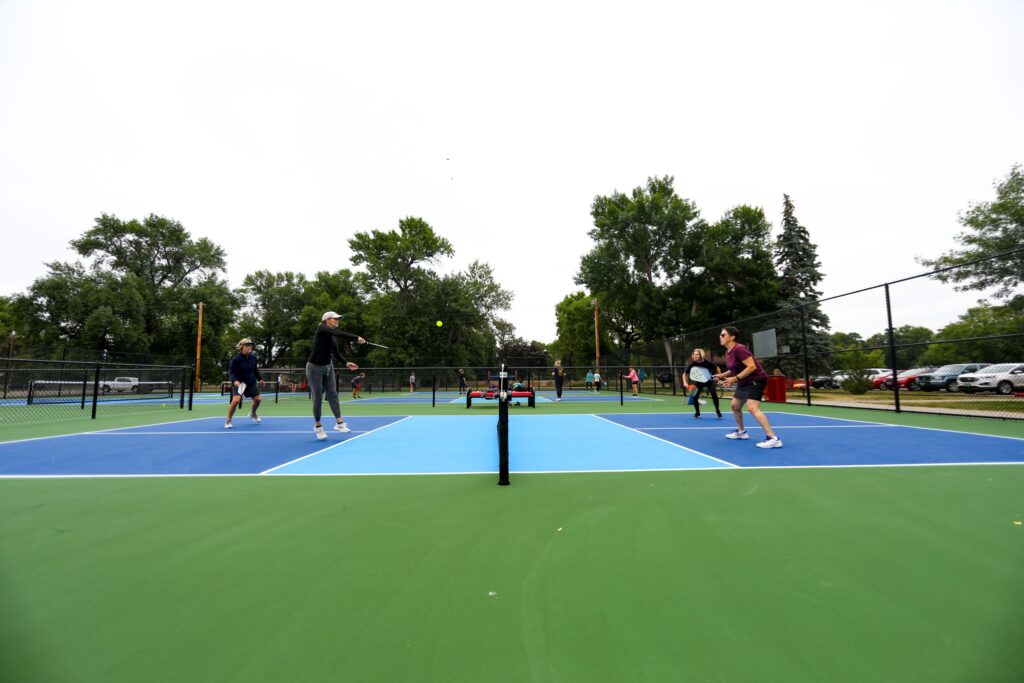 Adults playing pickleball on outdoor court. Active lifestyle program, fun sport activity. Pickleball players in action.
