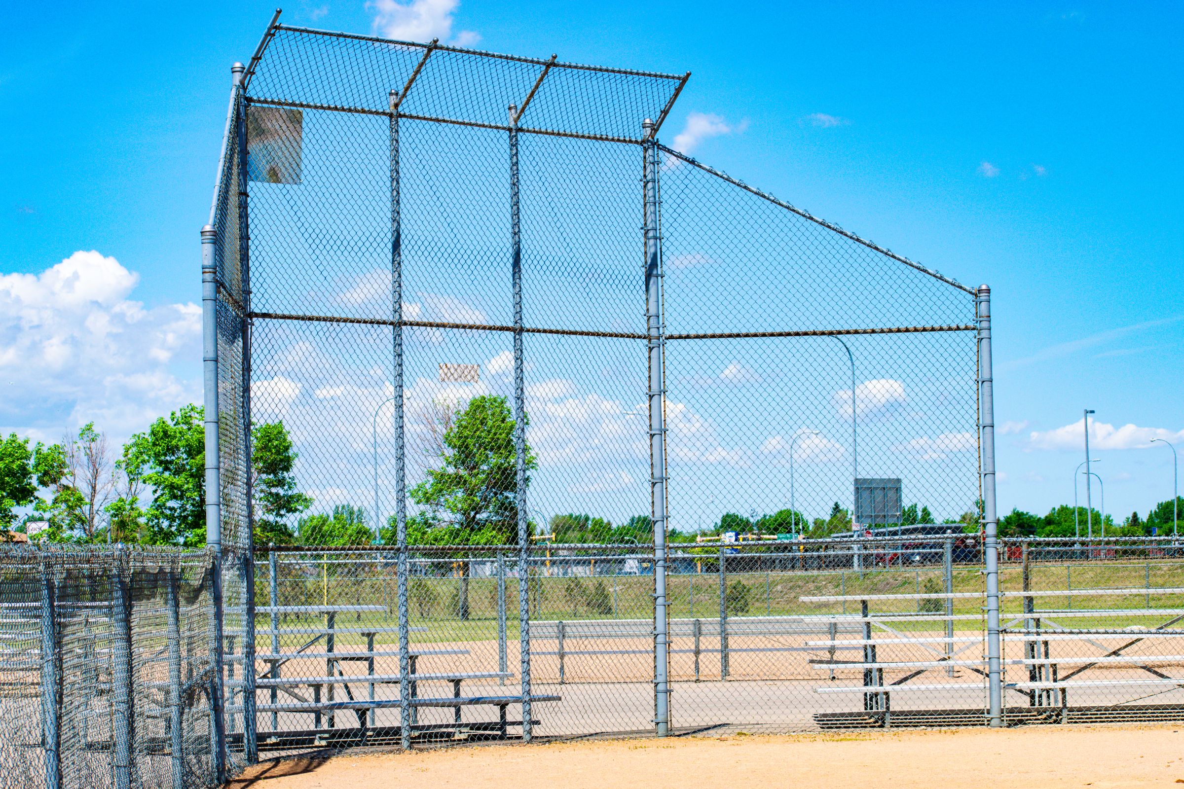 Baseball field with chain-link fence and bleachers on a sunny day. North Hill Fields sports facility, outdoor recreation.