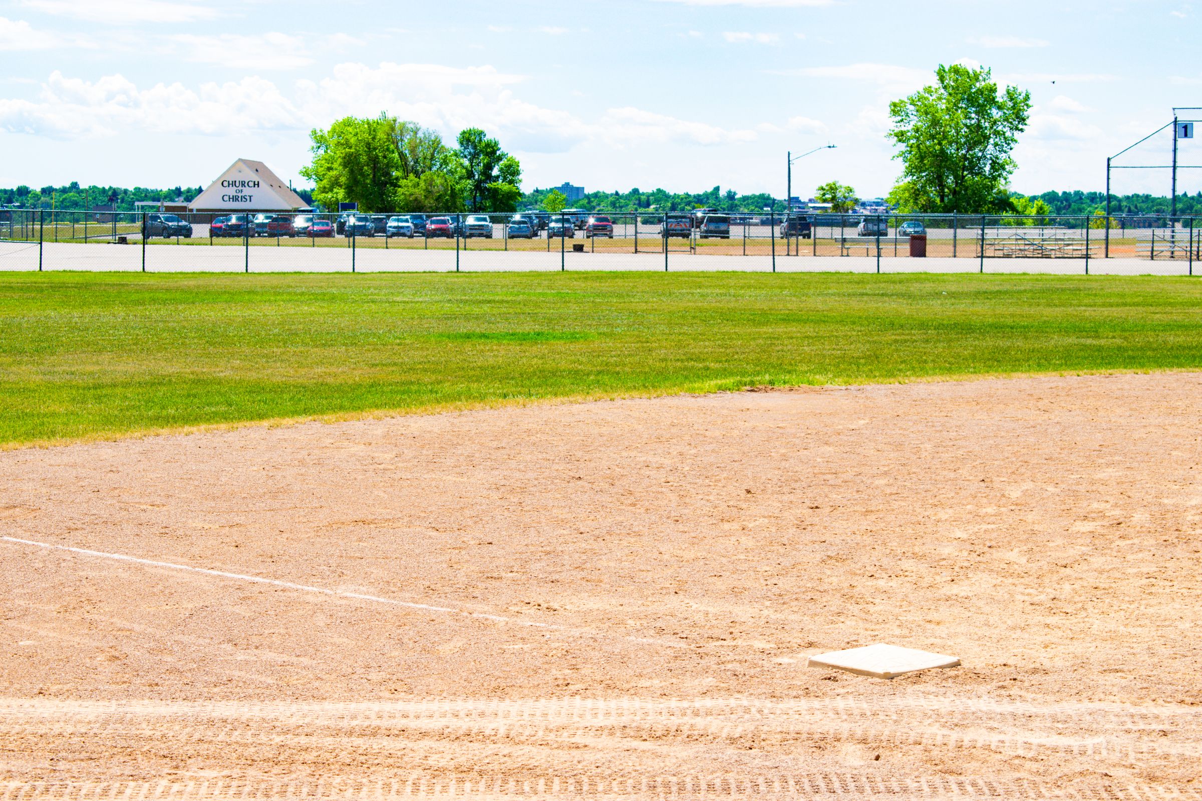 Third base on a baseball diamond. Empty ballfield with green grass under blue skies.
