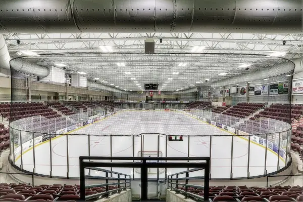 Interior view of the Maysa Arena, a hockey venue with seating and an ice rink ready for a game.