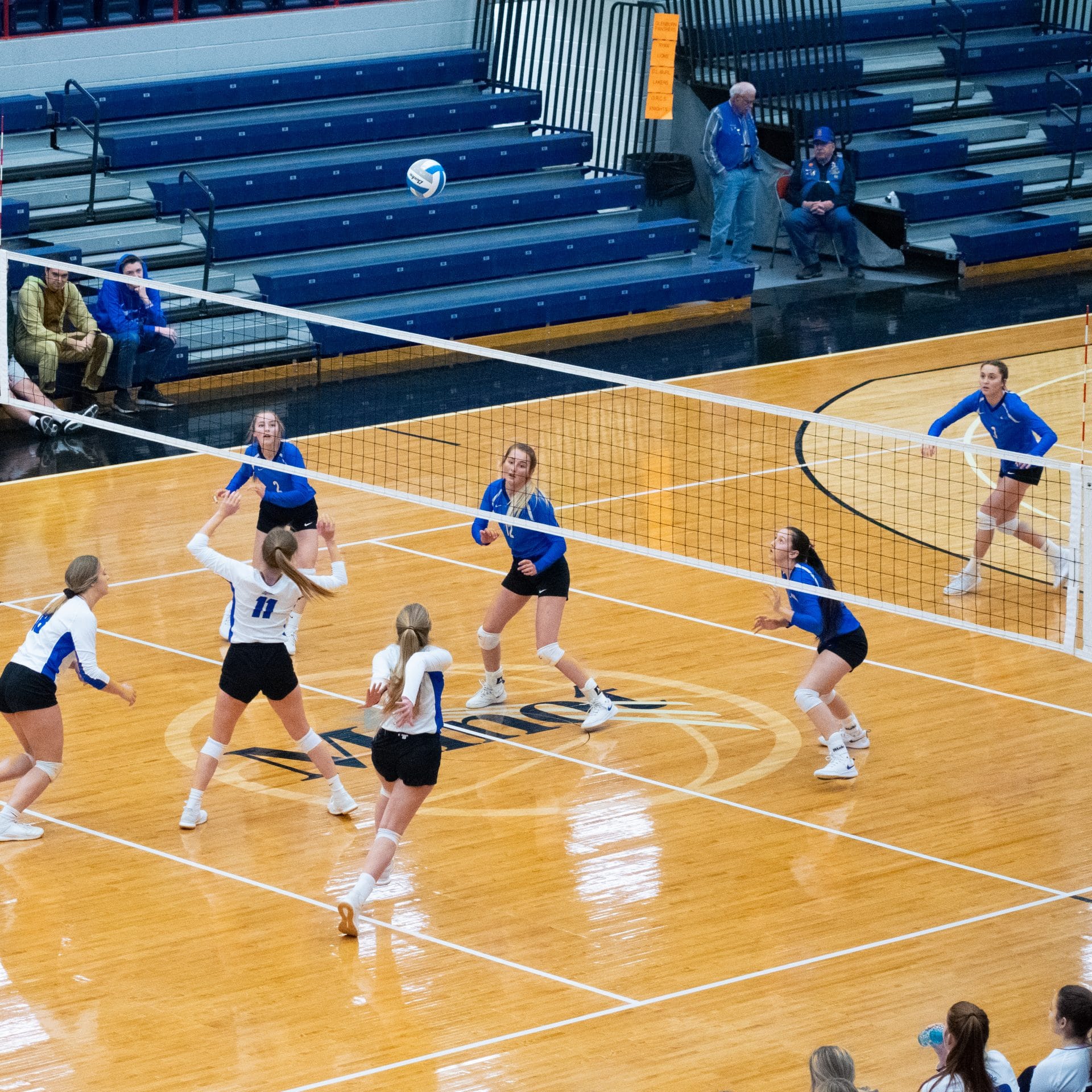 Girls from opposing volleyball teams prepare for a spike from the hitter.