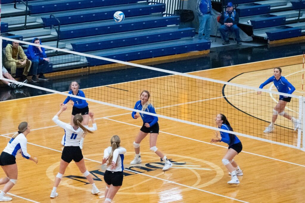 Girls from opposing volleyball teams prepare for a spike from the hitter.